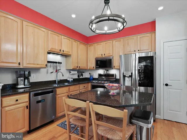 a kitchen with kitchen island granite countertop a sink stainless steel appliances and cabinets