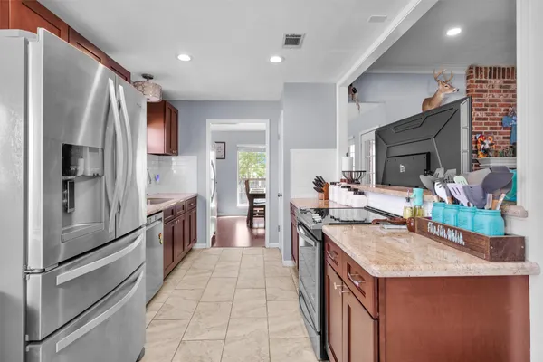 a kitchen with stainless steel appliances granite countertop a refrigerator a stove and a sink