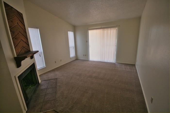 1906 West Loop, Unit D Austin, TX 78758 - Photo 3 of 5 Living area featuring a fireplace with a wood-finish mantel and chevron-patterned accent