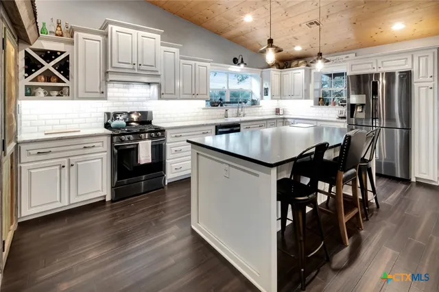 a kitchen with kitchen island granite countertop a sink cabinets and stainless steel appliances