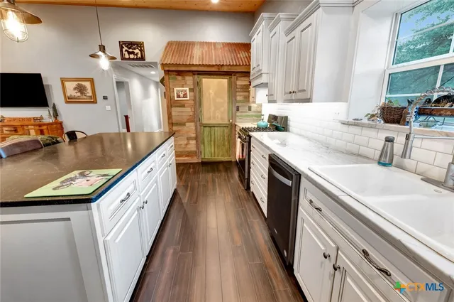 a kitchen with granite countertop a sink stove and refrigerator