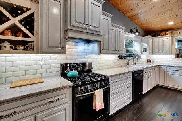a kitchen with stainless steel appliances granite countertop a sink a stove and cabinets
