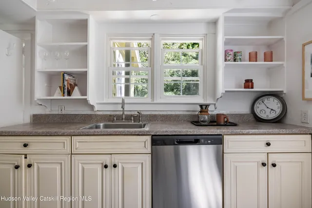 a kitchen with granite countertop a sink a clock and cabinets