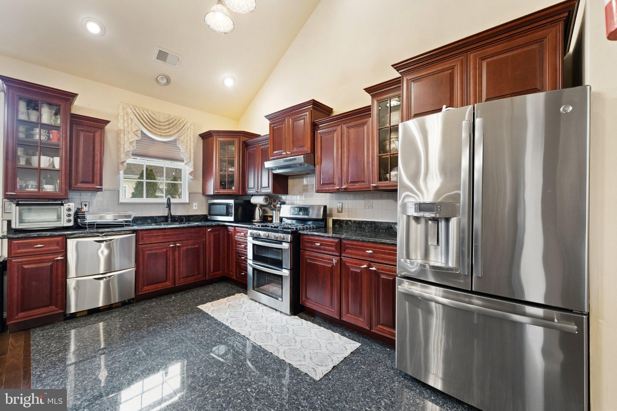 7 Spring Drive Dayton, NJ 08810 - Photo 8 of 24 a kitchen with stainless steel appliances granite countertop a refrigerator a stove a sink dishwasher a oven with wooden cabinets and floor