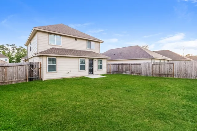 a view of a yard in front of a house with large yard plants and large tree