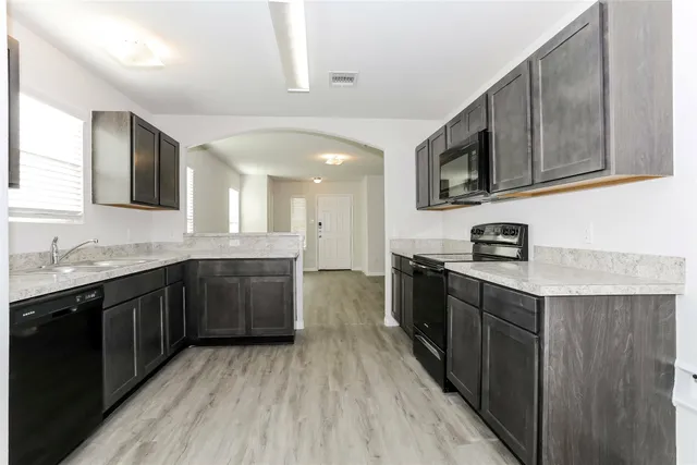 a large kitchen with stainless steel appliances granite countertop a lot of cabinets and wooden floor
