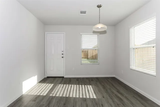 a view of an empty room with wooden floor and a window