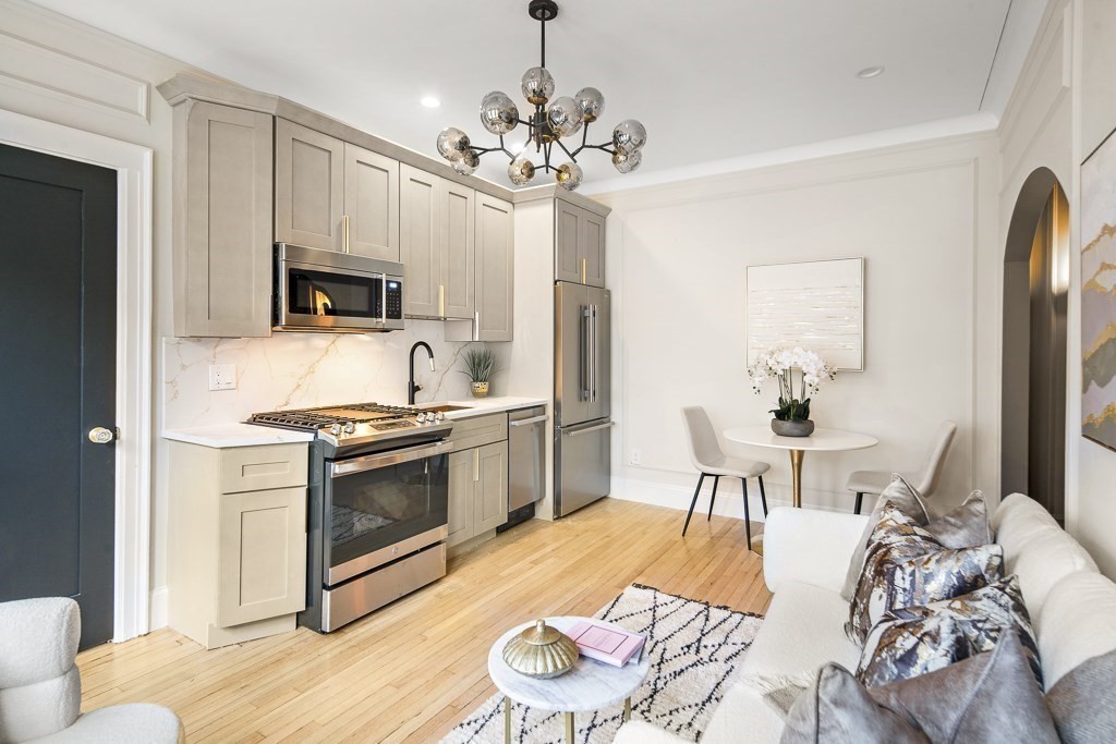 4 Chiswick Road, Unit 34 Boston, MA 02135 - Photo 11 of 22 a kitchen with stainless steel appliances a stove a sink dishwasher a refrigerator and a dining table with wooden floor