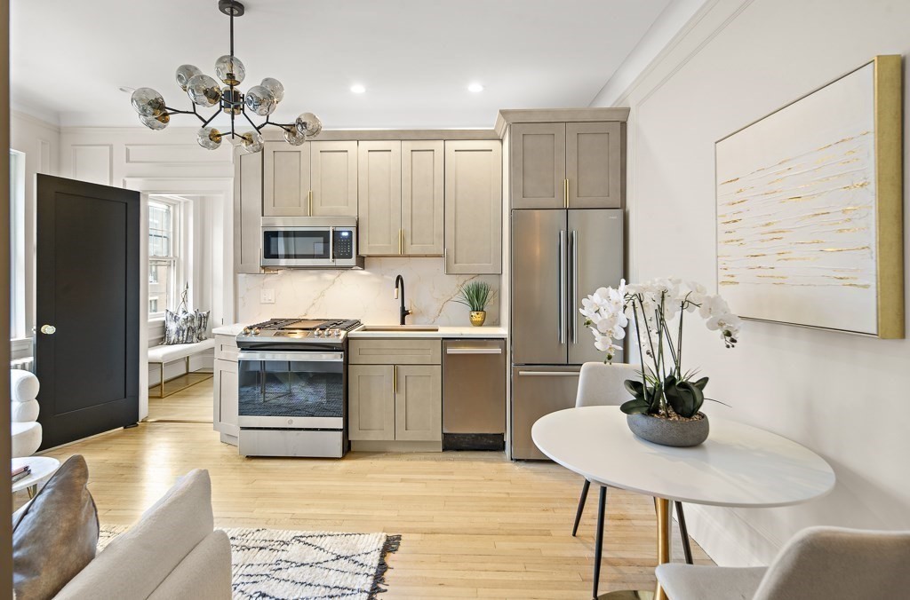 4 Chiswick Road, Unit 34 Boston, MA 02135 - Photo 10 of 22 a kitchen with stainless steel appliances kitchen island granite countertop a refrigerator a stove a sink dishwasher a dining table and chairs with wooden floor