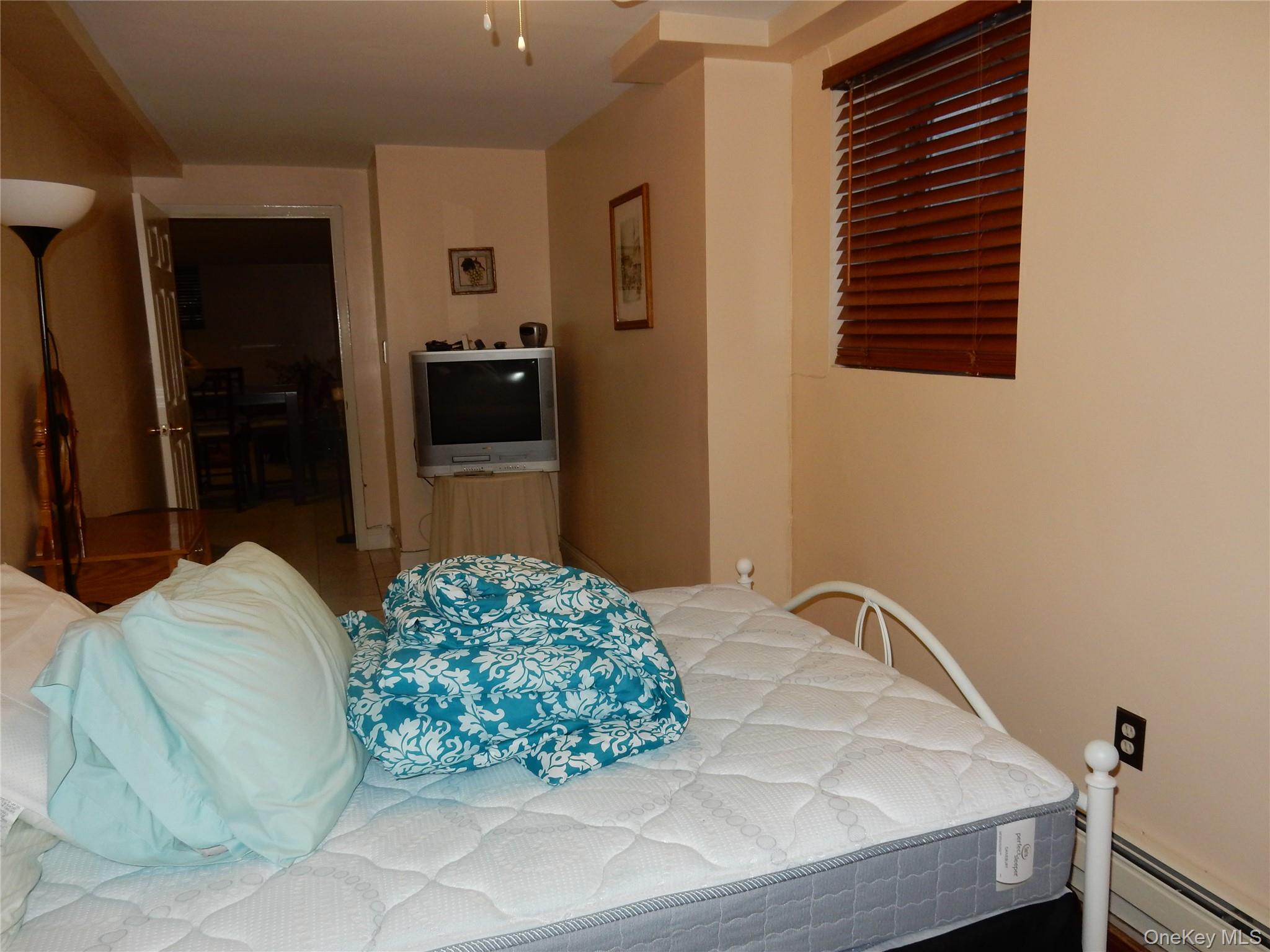 125-09 84th Road, Unit LL Queens, NY 11432 - Photo 5 of 7 a bedroom with a bed and a television