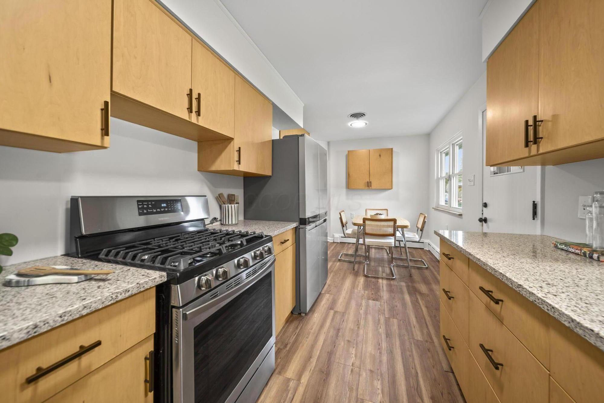 3496 Wicklow Road Columbus, OH 43204 - Photo 13 of 53 Stainless steel gas range, LVP flooring, light-toned cabinetry, speckled countertops, and a double-door refrigerator