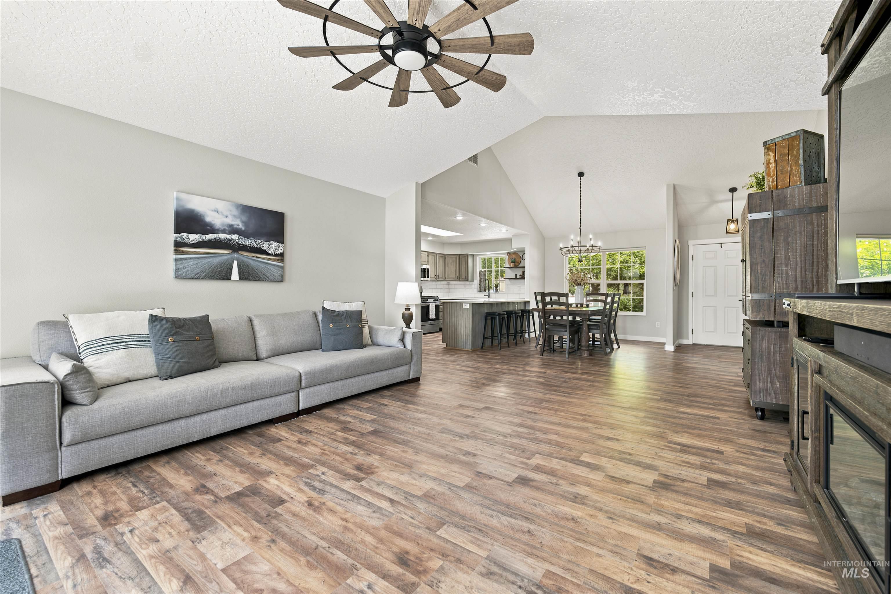 24864 Coventry Drive Caldwell, ID 83607 - Photo 8 of 49 Spacious living area featuring wood-finish flooring, vaulted ceiling, and a ceiling fan with integrated lighting