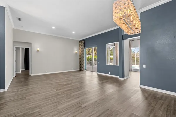an empty room with wooden floor a ceiling fan and windows