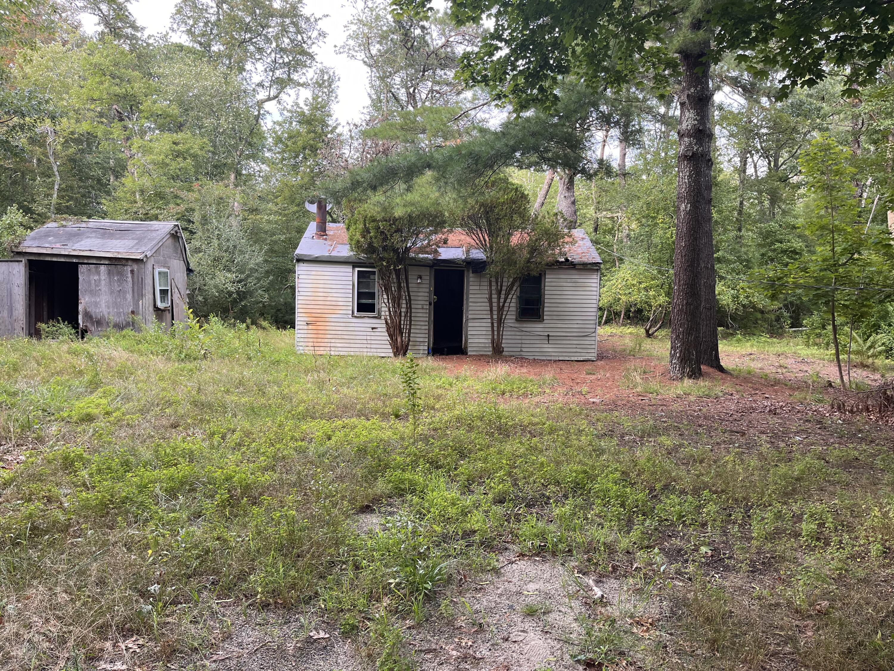 52 Upper County Road Dennis Port, MA 02639 - Photo 2 of 3 a view of a house with a small yard and large trees