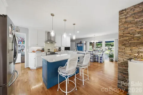 a kitchen with stainless steel appliances kitchen island granite countertop a dining table chairs and a oven