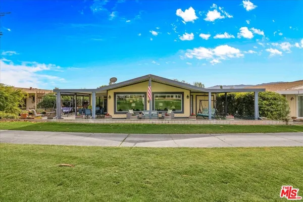 a view of a house with a big yard and large trees