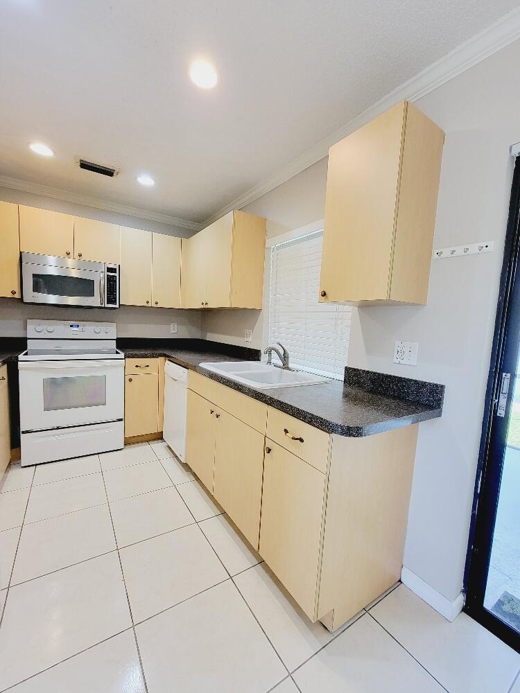 12785 Peconic Court, Unit 12785 Wellington, FL 33414 - Photo 4 of 12 a kitchen with stainless steel appliances granite countertop a sink and a stove