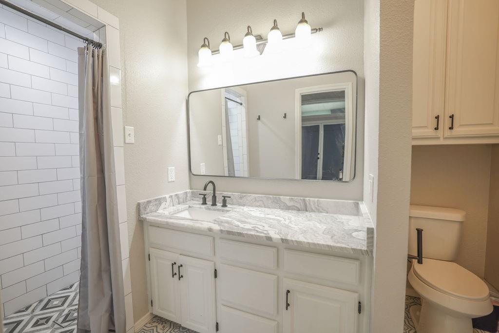 9501 Oakwood Road Quinlan, TX 75474 - Photo 13 of 34 a bathroom with a granite countertop sink and a mirror with toilet