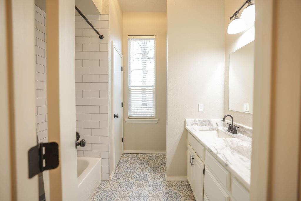 9501 Oakwood Road Quinlan, TX 75474 - Photo 18 of 34 a bathroom with a granite countertop sink a mirror and a shower