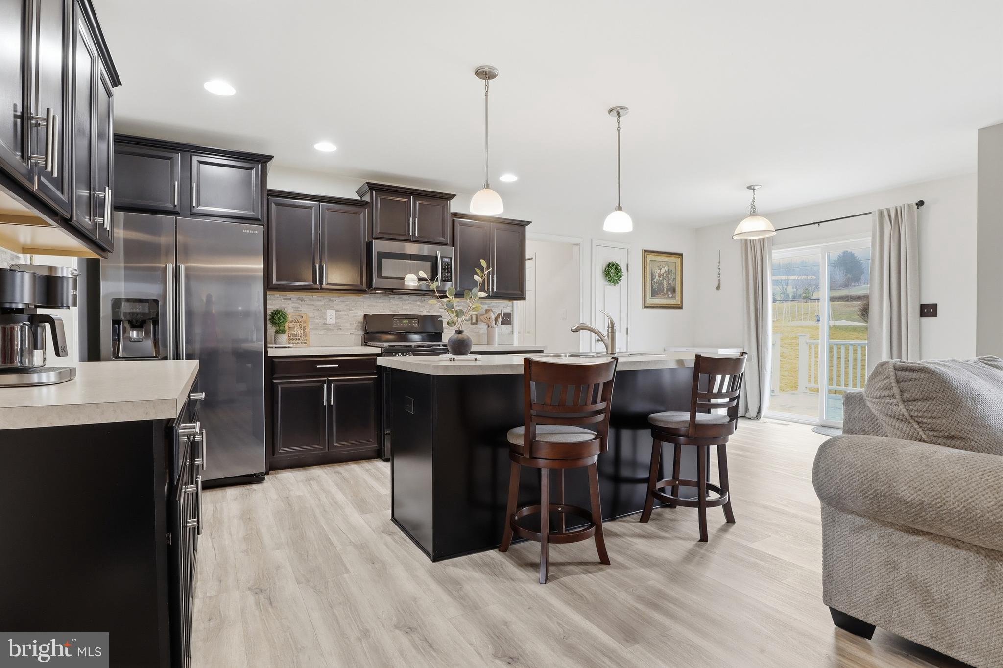 99 McIntosh Lane Aspers, PA 17304 - Photo 11 of 63 a kitchen with stainless steel appliances kitchen island granite countertop a table chairs and a wooden floor