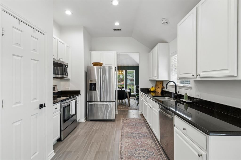 7703 Worthing Street Dallas, TX 75252 - Photo 5 of 21 a kitchen with stainless steel appliances a refrigerator sink and cabinets