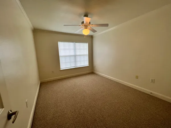 an empty room with a chandelier fan and windows