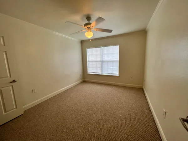 an empty room with a chandelier fan and windows