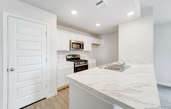 a kitchen with a refrigerator a stove and white cabinets