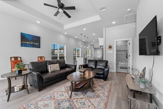 a living room with furniture kitchen view and a wooden floor