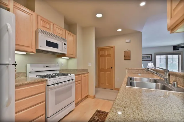 a kitchen with stainless steel appliances granite countertop a stove a sink and a microwave