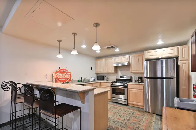 a kitchen with granite countertop a sink cabinets stainless steel appliances and a dining table