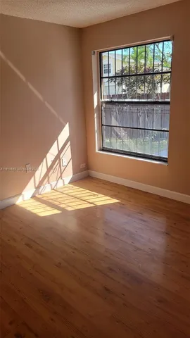 a view of empty room with window and wooden floor