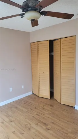 an empty room with wooden floor closet and windows