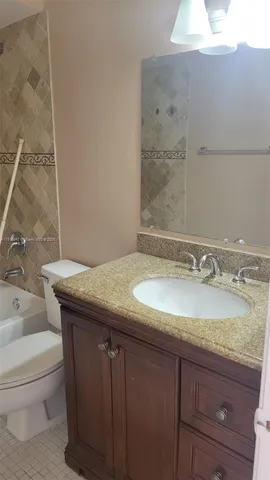 a bathroom with a granite countertop sink a toilet and bathtub