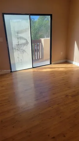 a view of a room with wooden floor and a floor to ceiling window
