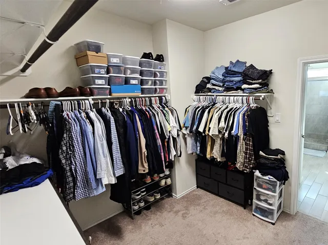 a view of walk in closet with clothes and shoes
