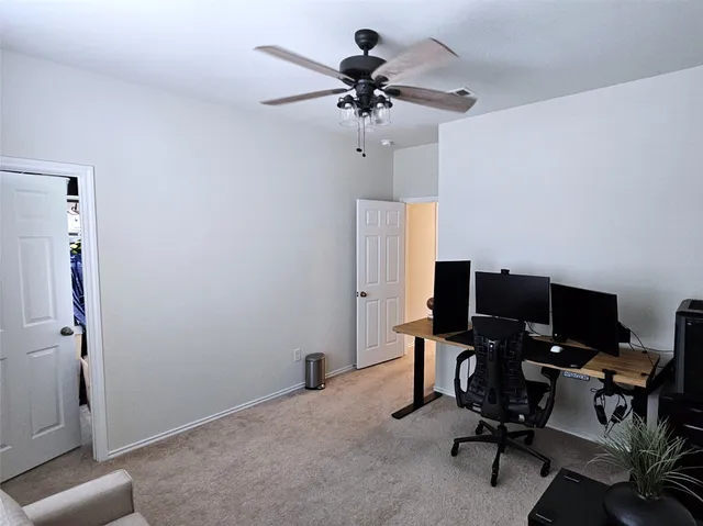 a view of a workspace with furniture and a ceiling fan