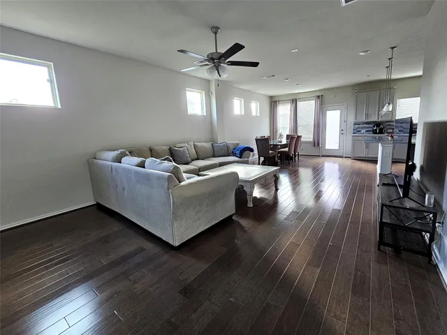a living room with couches and kitchen view with wooden floor