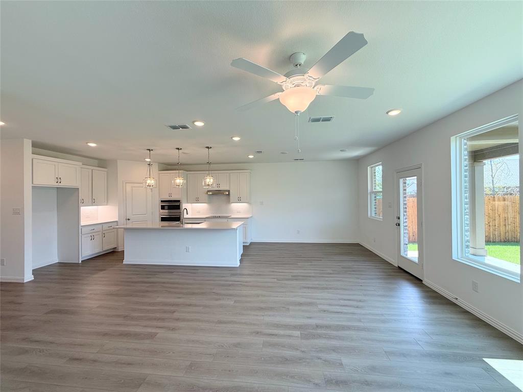 713 Roanoke Drive Princeton, TX 75407 - Photo 40 of 40 Kitchen with recessed lighting, open floor plan, white cabinetry, light wood finished floors, and a kitchen island with sink