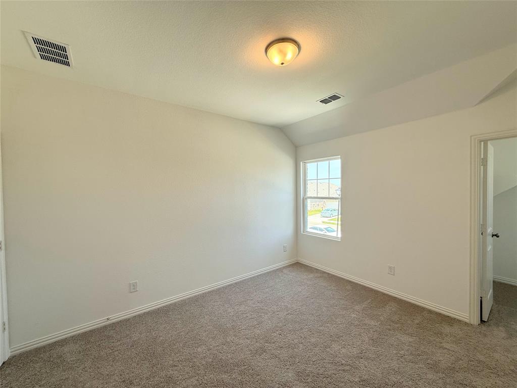 713 Roanoke Drive Princeton, TX 75407 - Photo 21 of 40 Unfurnished bedroom featuring vaulted ceiling, carpet floors, a walk in closet, and a textured ceiling