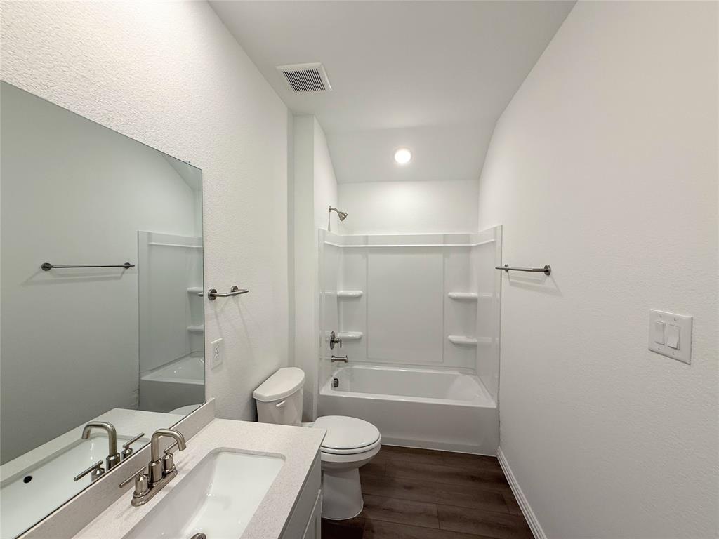 713 Roanoke Drive Princeton, TX 75407 - Photo 24 of 40 Bathroom featuring washtub / shower combination, dark wood-style flooring, vanity, and a textured wall