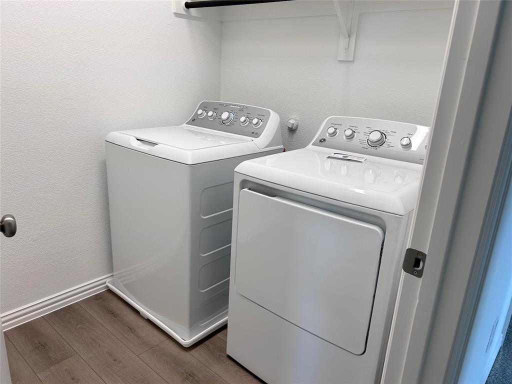 713 Roanoke Drive Princeton, TX 75407 - Photo 30 of 40 Laundry area featuring a textured wall, wood finished floors, and separate washer and dryer
