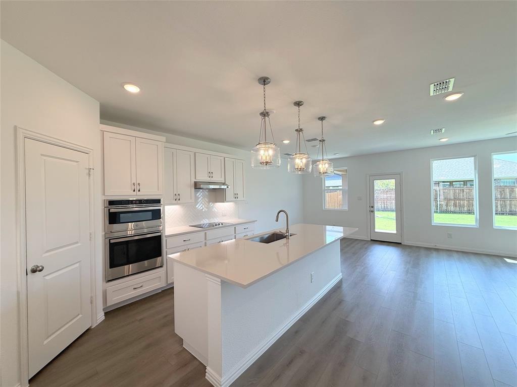713 Roanoke Drive Princeton, TX 75407 - Photo 7 of 40 Kitchen with pendant lighting, white cabinets, backsplash, an island with sink, and dark wood-type flooring