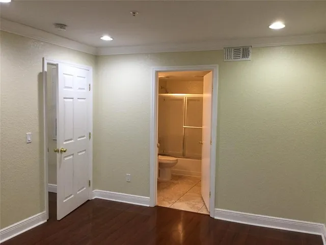 an empty room with wooden floor and closet area