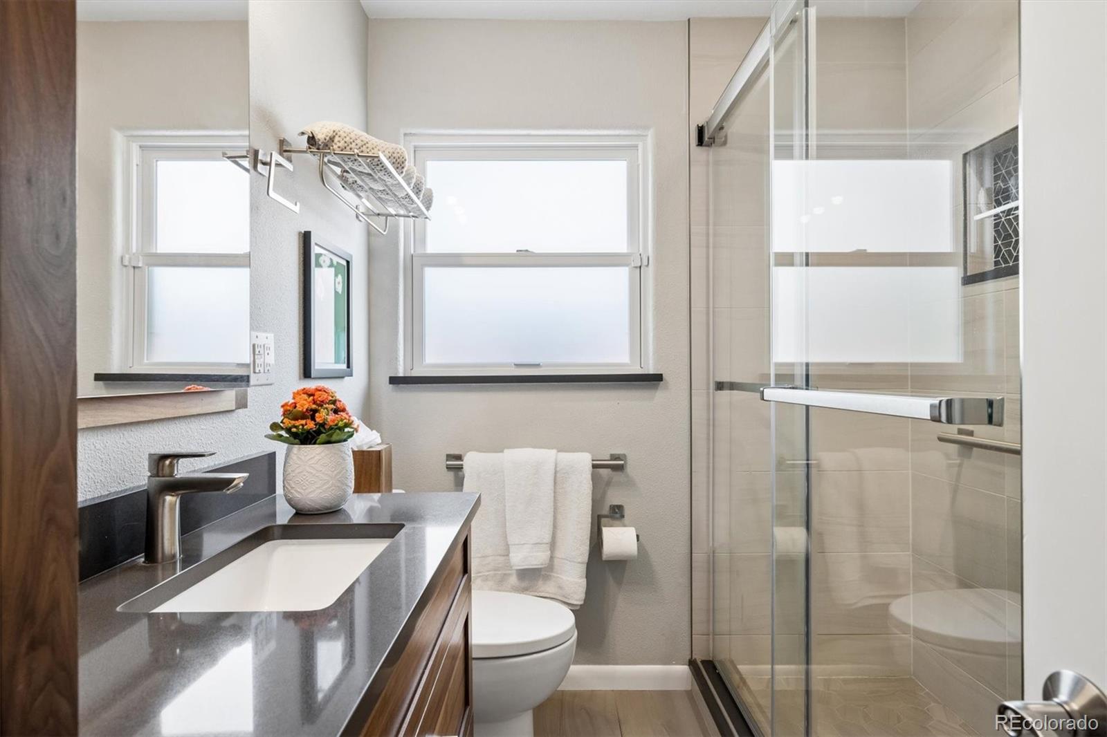 730 Ivanhoe Street Denver, CO 80220 - Photo 22 of 34 a bathroom with a granite countertop sink toilet a mirror and shower