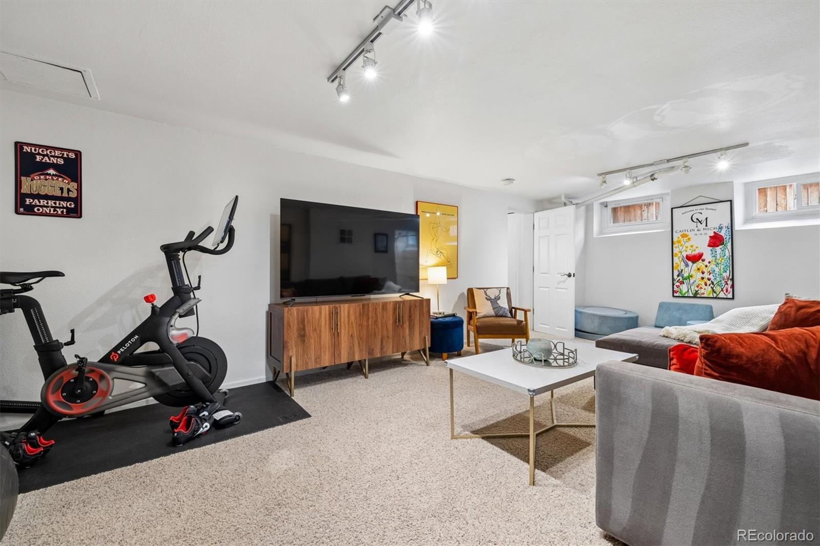 730 Ivanhoe Street Denver, CO 80220 - Photo 25 of 34 a living room with furniture a flat screen tv and gym equipment