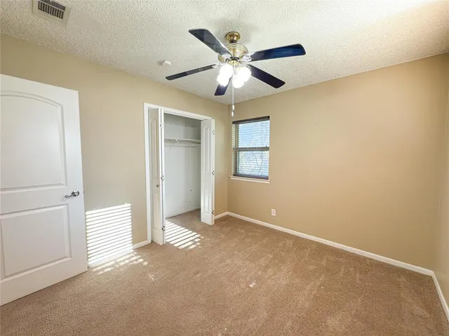 an empty room with windows and fan