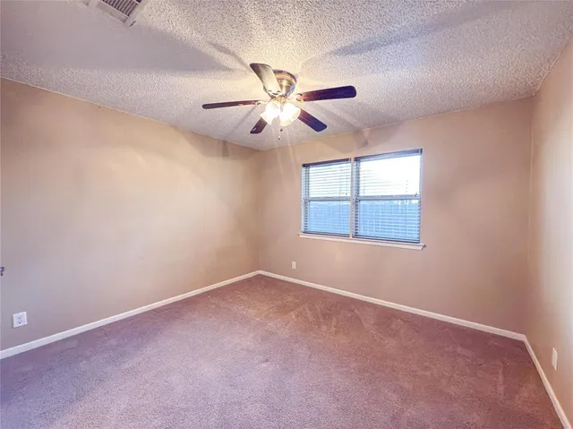 an empty room with windows and fan chandelier fan