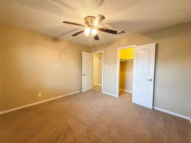 an empty room with closet and a chandelier fan