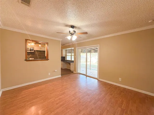 an empty room with wooden floor chandelier fan and windows